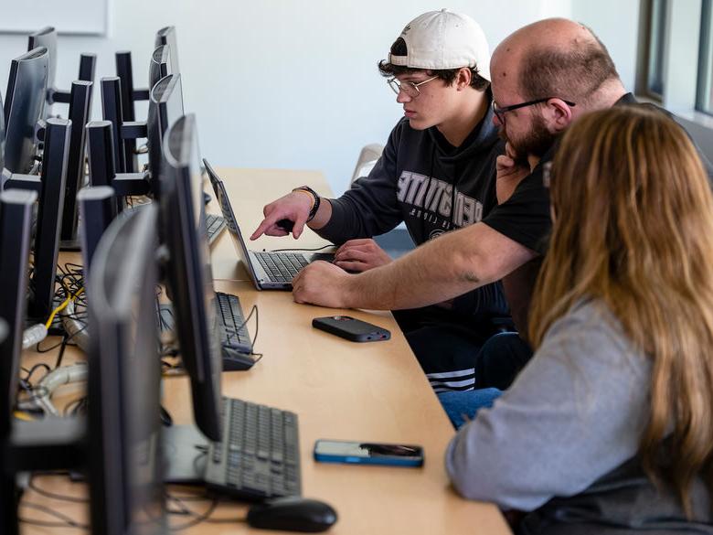 Students working with a Professor on a computer